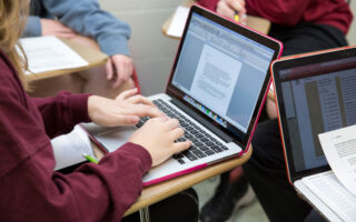 student typing on a laptop in class